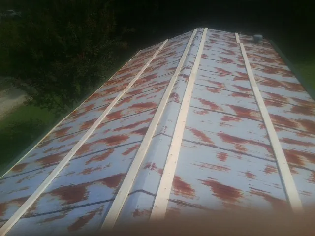 Rusted metal roof panels with new wood purlins before replacement — Storm Damage Roof Repair in Reddick by Roofing Brothers