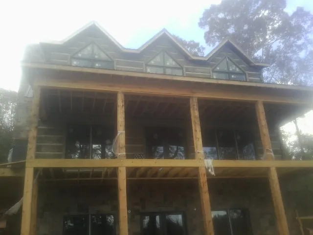 Dormers and porch framing on a large log home under construction — Roof Coating work by our crew in Reddick