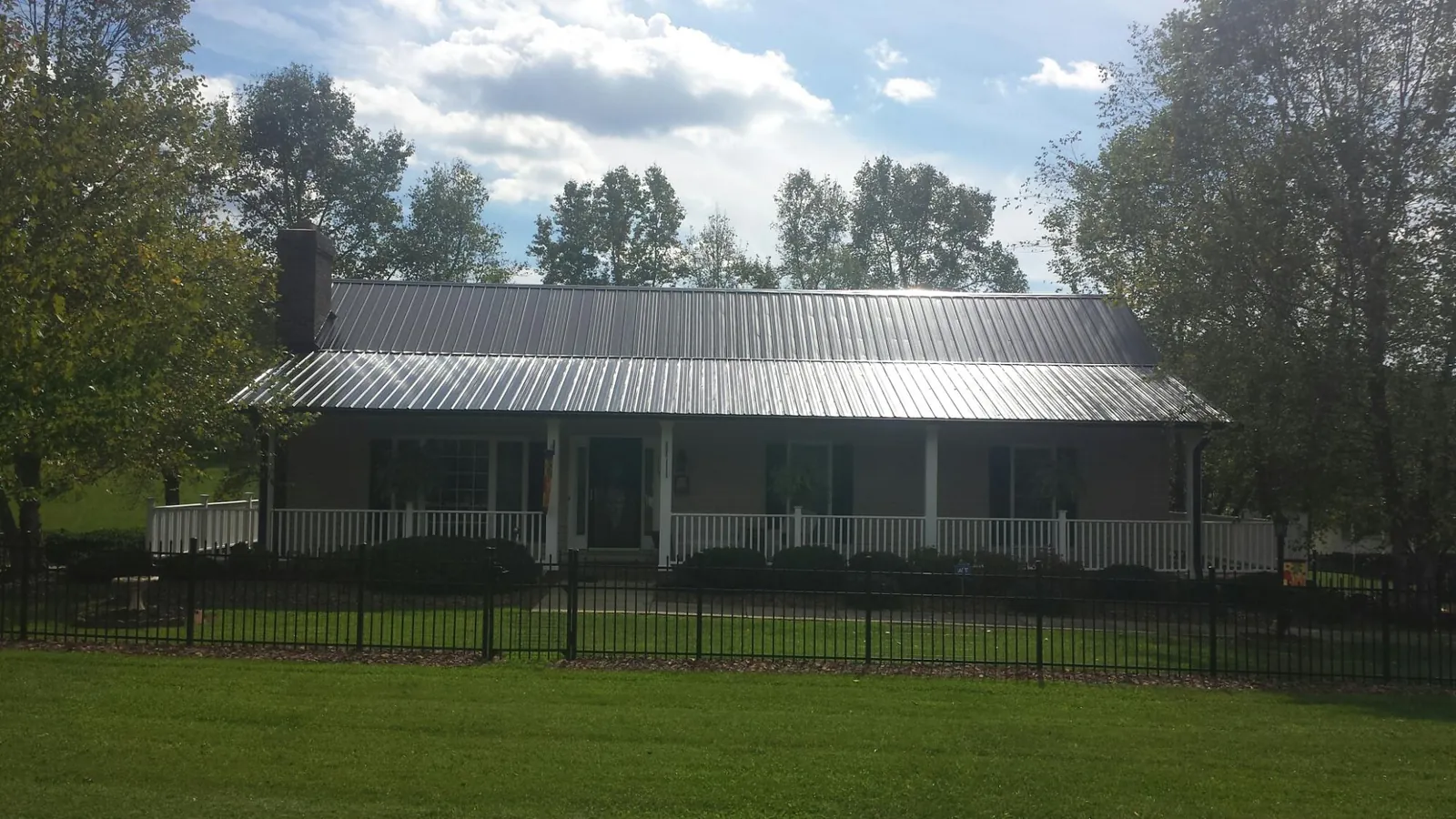 Gray metal roof on a brick ranch with a full width front porch — Gutter Guard Installation work by our crew in Reddick