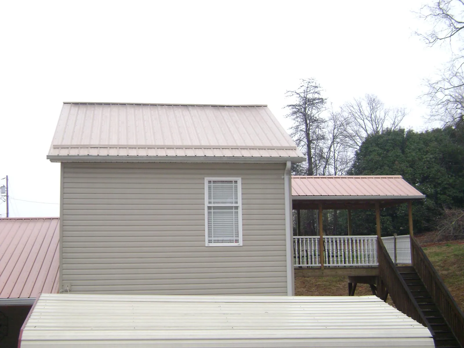 Tan metal roofs on a two story addition and attached porch, from a Roof Replacement job in Reddick